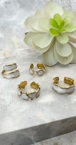 Gold rings with white stones beside a succulent.