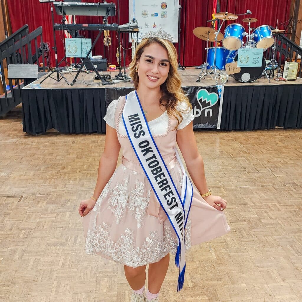 Woman wearing 'Miss Oktoberfest' sash and tiara.