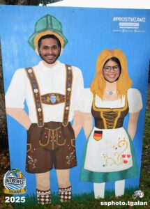 Two people posing in Oktoberfest cutout, Miami 2025.