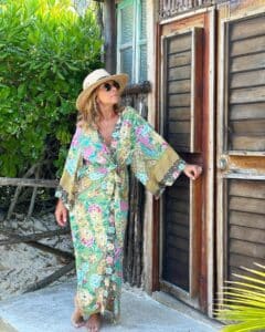 Woman in floral dress by rustic wooden door.