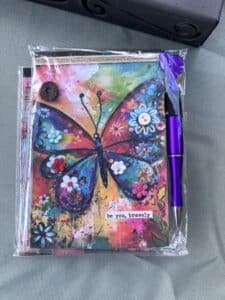 Colorful butterfly journal with motivational text and pen.