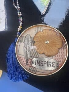 Decorative plate with 'Inspire', feather, and tassel.