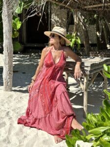 Woman in red dress relaxing on a tropical beach.