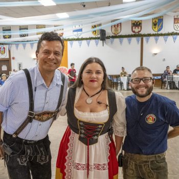 Three people in traditional German attire at event.