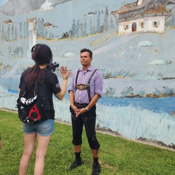 Filming a man in front of mural art.