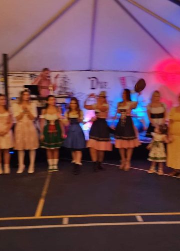 People in traditional costumes at event under tent.