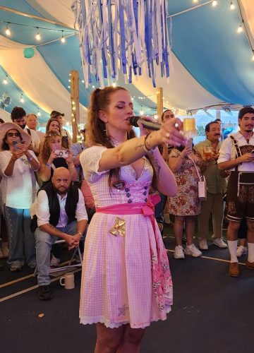 Singer performing at crowded festival under tent lights.