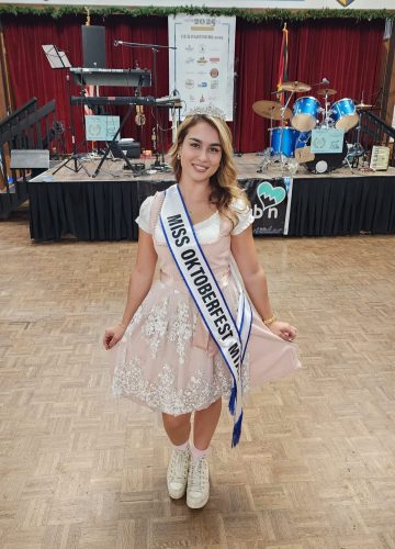 Miss Oktoberfest winner in traditional dress on stage.