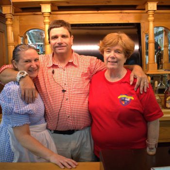 Three people at a bar smiling.